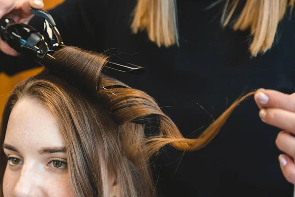 La peluquera maestra riza suavemente a la chica rizadora en un salón de belleza. Peinado del cabello — Foto de Stock