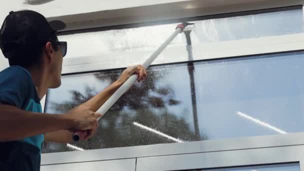 Profesionální úklidový pracovník myje okna speciální pěnou a čistí je. — Stock video