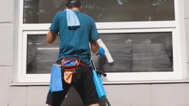 Profesjonalny pracownik firmy sprzątającej myje okna w firmach specjalnymi chemikaliami — Wideo stockowe