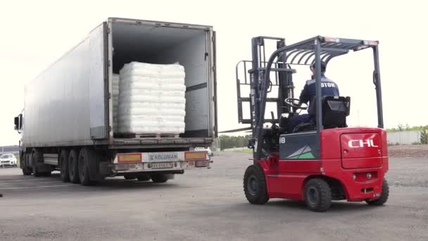 Ufa, Rusko, 30. června2020. Výrobní závod na polypropylen. Muž na vysokozdvižném vozíku pracuje ve velkém skladišti, vykládá pytle se surovinami — Stock video