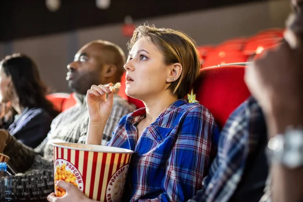 Amigos están viendo una película en el cine con palomitas de maíz. La gente se sienta en los sillones del cine y mira la pantalla — Foto de Stock