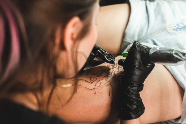 Profesyonel bir dövme sanatçısı, bir kadının bacağına mürekkeple siyah beyaz dövme yapar. Derinin dövmesi.. — Stok fotoğraf