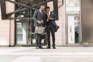 Siyahi Afro-Amerikan iş adamının iki arkadaşı bir şehir bloğunda takım elbiseli. Arkadaşlık ve iş ortaklığı