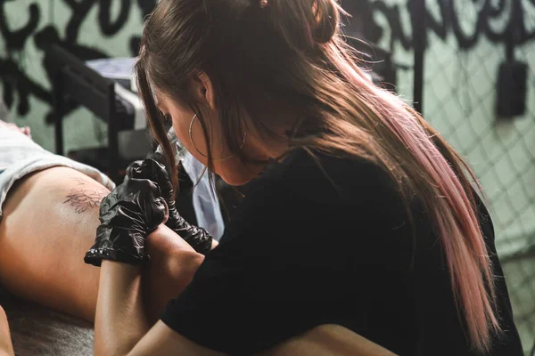 Donna tatuatrice che fa tatuaggi in studio, che fa tatuaggi sul corpo. primo piano — Foto Stock
