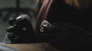 Profesyonel bir dövme sanatçısı, bir kadının bacağına mürekkeple siyah beyaz dövme yapar. Derinin dövmesi..
