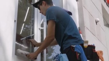 Profesyonel bir erkek işçi temizlik ve pencereleri temizlemekle meşgul. Temizlik servisi