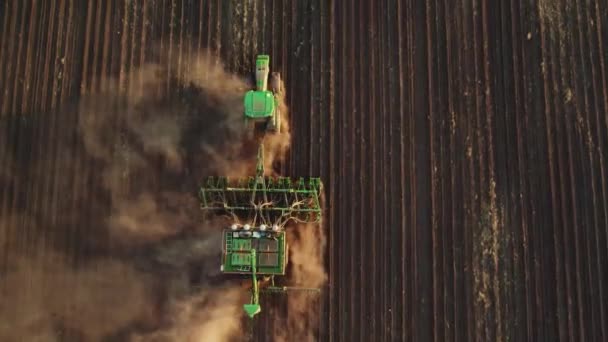Imágenes de vídeo aéreas de 4K de un tractor arando un campo y el viento levantando polvo. Preparación del suelo para la próxima temporada de cosecha — Vídeo de stock