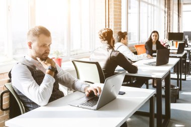 Gündelik giyinen genç iş adamları ofiste birlikte çalışıyorlar. Ekip iş başında.