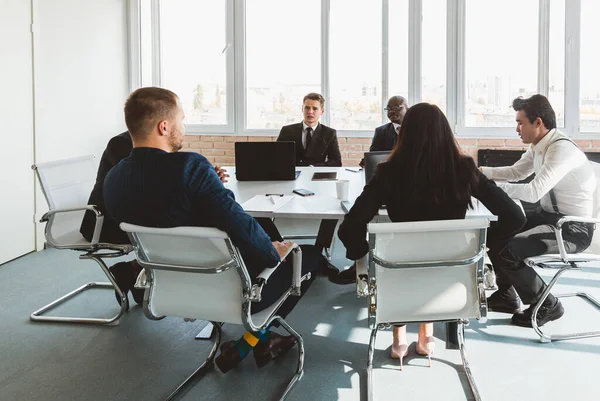 Ofis masasında iş arkadaşlarıyla otururken çalışan ve iletişim kuran bir grup genç iş adamı. iş toplantısı