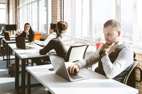 Gündelik giyinen genç iş adamları ofiste birlikte çalışıyorlar. Ekip iş başında.