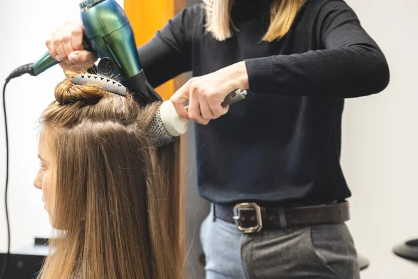 Master parrucchiere donna asciuga i capelli delle ragazze con un asciugacapelli e pettini dopo il lavaggio nel salone di bellezza — Foto Stock