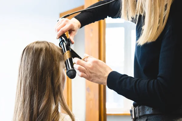 La peluquera maestra riza suavemente a la chica rizadora en un salón de belleza. Peinado del cabello — Foto de Stock