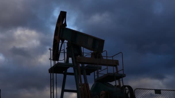 夕方の空を背景に、吸盤棒ポンプが作動して油を汲み上げています。油井サービス — ストック動画