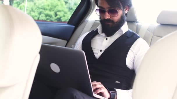 Indický podnikatel pracující s notebookem na zadním sedadle auta — Stock video