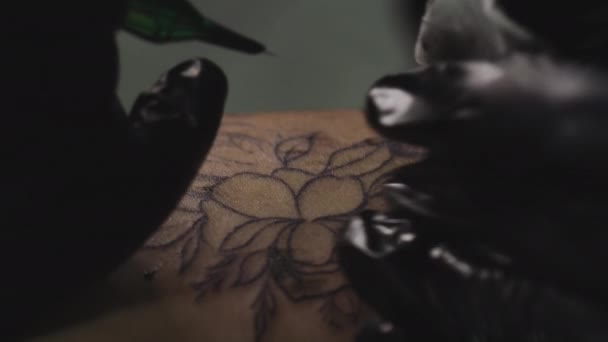 Profesionální tetovací umělkyně dělá tetování ve studiu, zblízka. Tmavé video 4k — Stock video