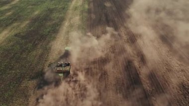 Traktörün üstünden 4K drone atışı tarlada çalışıyor ve toprağı sürüp toz kaldırıyor. Gelecek hasat mevsimi için toprağı hazırlıyor ve ekiyoruz.