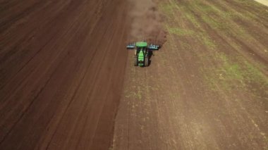 Traktörün üstünden 4K drone atışı tarlada çalışıyor ve toprağı sürüp toz kaldırıyor. Gelecek hasat mevsimi için toprağı hazırlıyor ve ekiyoruz.