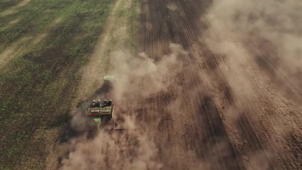 Traktörün üstünden 4K drone atışı tarlada çalışıyor ve toprağı sürüp toz kaldırıyor. Gelecek hasat mevsimi için toprağı hazırlıyor ve ekiyoruz. — Stok video