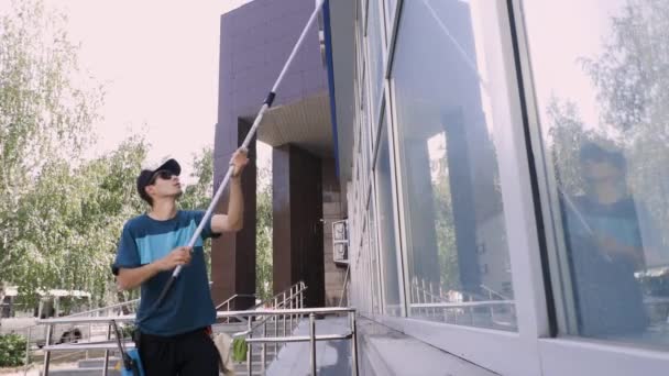 Крупним планом відео фахівця клінінгової служби миє і очищає вікна і фасад будівлі — стокове відео