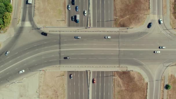 上から道路の交差点に表示します。移動中の車両とパス分割を持つ複数レーンの道路の空中ドローン映像。大都市での車の交通 — ストック動画