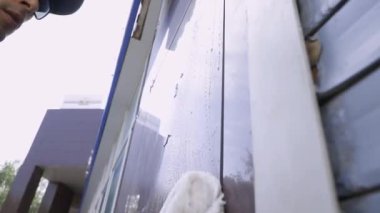 Bir temizlik uzmanının yakın çekim videosu binanın pencerelerini ve cephelerini yıkıyor ve temizliyor.