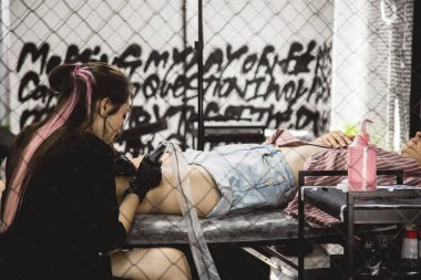 Profesyonel bir dövme sanatçısı, bir kadının bacağına mürekkeple siyah beyaz dövme yapar. Derinin dövmesi..