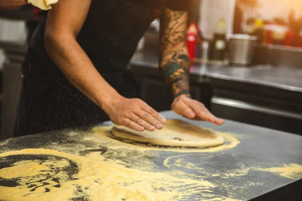 Professional chef cooking in the kitchen restaurant at the hotel, preparing dinner. A cook in an apron makes a pizza. — Stock Photo, Image