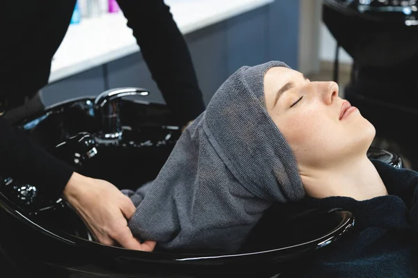 Master kobieta fryzjer starannie owija dziewczyny głowę w ręcznik przed stylizacji w salonie piękności. Widok z góry — Zdjęcie stockowe