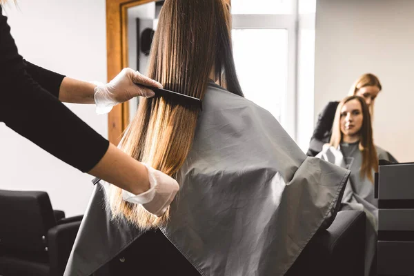Maestro peluquero peina el cabello de las niñas después de lavar y antes de peinar en un salón de belleza. De cerca. — Foto de Stock