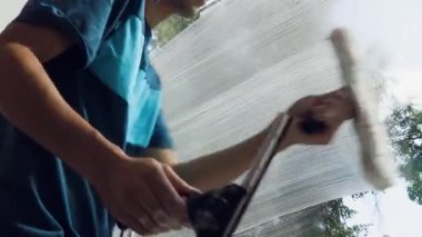 Tulumlu profesyonel erkek işçi temizlik ve pencereleri ve giriş lobisini temizliyor.