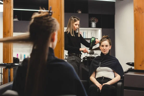 Master γυναίκα κομμωτήριο στεγνώνει τα κορίτσια μαλλιά με στεγνωτήρα μαλλιών μετά το πλύσιμο σε ένα σαλόνι ομορφιάς. — Φωτογραφία Αρχείου