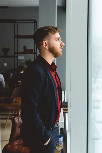 Retrato de un joven empresario con un traje en la oficina. Primer plano de pie junto a la ventana — Foto de Stock