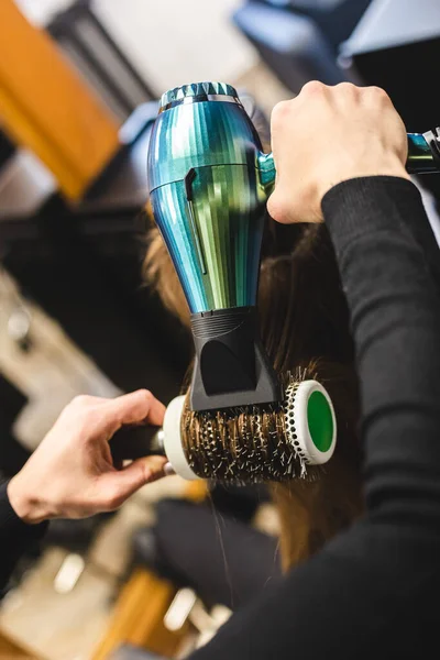 Maestra mujer peluquería seca el pelo de las niñas con un secador de pelo y peines después de lavarse en el salón de belleza. — Foto de Stock
