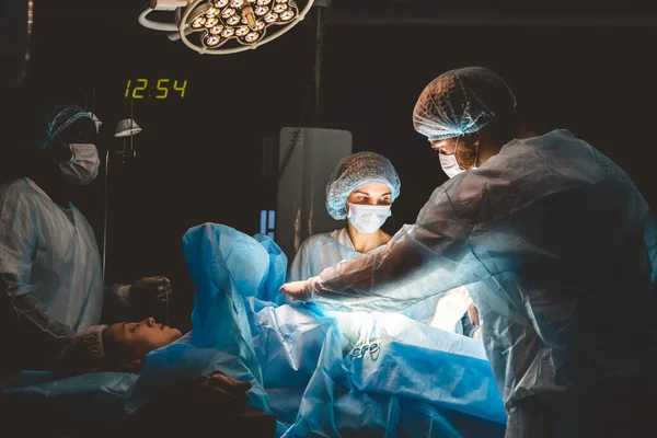O cirurgião sênior na sala de cirurgia, onde o paciente está esperando por ele, e ele começa a operação. Hospital Real Moderno com Equipamento Autêntico. — Fotografia de Stock