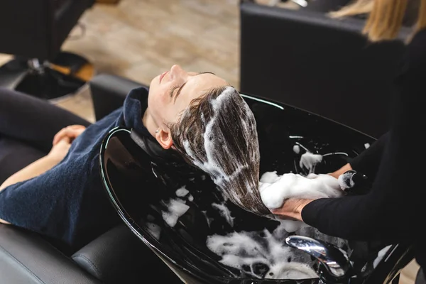 Mistryně žena kadeřnice myje vlasy dívky s šamponem před styling v salonu krásy. Pohled shora — Stock fotografie