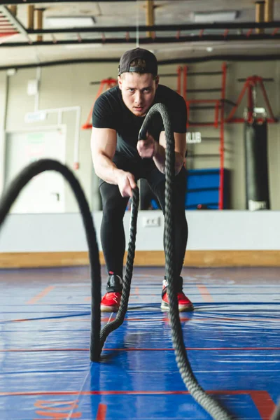 Kötéllel keresztezve. A sportoló az edzőteremben edz.. — Stock Fotó