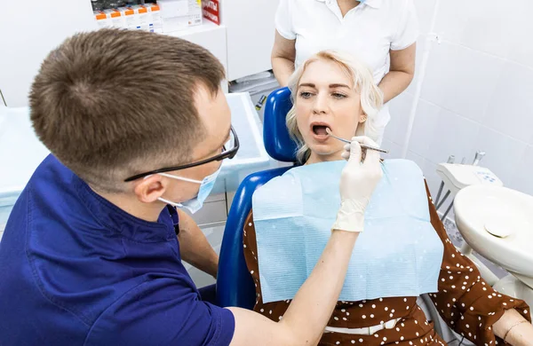 치과 개념입니다. 전문 치과 서비스와 통증없는 현대 장비. 의사는 그 여자 와상의 하여 치료를 하고, 검사를 하고 치료 계획을 작성 한다 — 스톡 사진