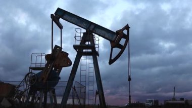 Siluet emici çubuk pompası çalışır ve akşam gökyüzünün arka planına yağ pompalar