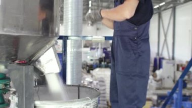 Bir işçi, otomatikman karıştırıcıdan çıkan hammaddeleri fabrikadaki varillere ve poşetlere doldurur. Polipropilen ürünlerinin üretimi.