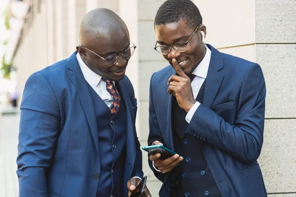 Um par de empresários negros afro-americanos amigos de terno estão falando enquanto estão de pé na rua. Encontro de negócios ao ar livre — Fotografia de Stock