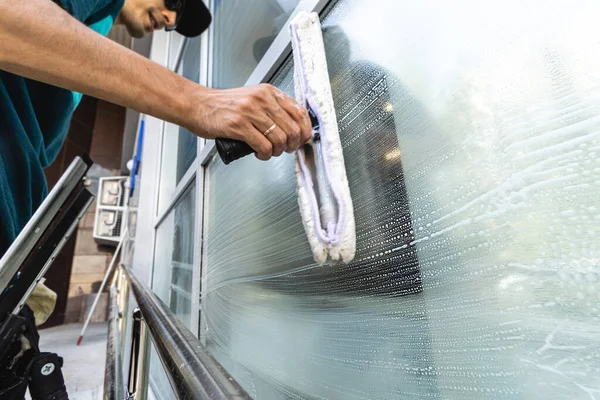 Un empleado de un servicio de limpieza profesional en overoles lava la fachada y las ventanas con dispositivos especiales — Foto de Stock