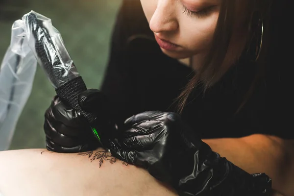 Profesyonel kadın dövme sanatçısı stüdyoda dövme yapıyor, yakın plan. Karanlık fotoğrafçılık — Stok fotoğraf