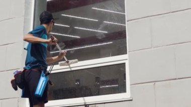 Temizlik şirketinden profesyonel bir işçi şirketin camlarını özel kimyasallarla siler.