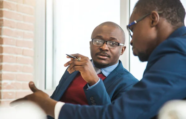Двоє темношкірих партнерів афроамериканського бізнесмена під час зустрічі на ноутбуку в офісі. Доступні приватні курси та дистанційне навчання. Стокове Фото