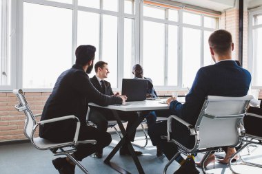 Ofis masasında iş arkadaşlarıyla otururken çalışan ve iletişim kuran bir grup genç iş adamı. iş toplantısı