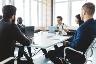 Ofis masasında iş arkadaşlarıyla otururken çalışan ve iletişim kuran bir grup genç iş adamı. iş toplantısı