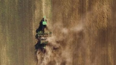 Bir traktörün tarlayı sürdüğü ve rüzgarın tozu savurduğu 4K hava görüntüsü. Gelecek hasat mevsimi için toprağı hazırlıyorum.