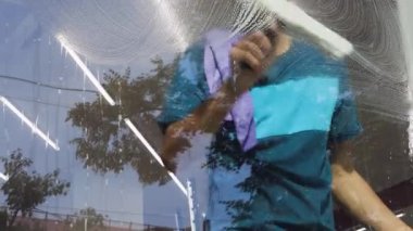 Temizlik şirketinden profesyonel bir işçi şirketin camlarını özel kimyasallarla siler.