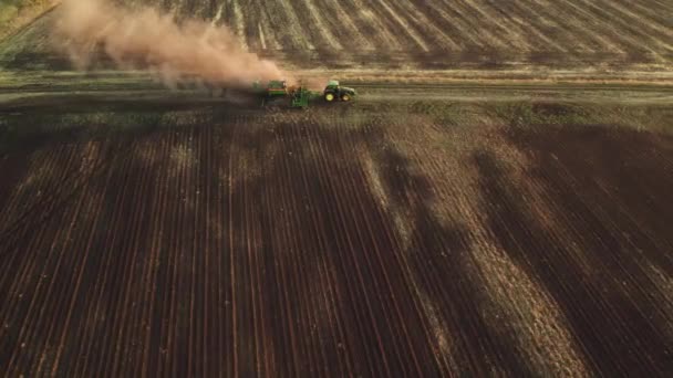4К видео с воздуха, где трактор вспахивает поле и ветер поднимает пыль. Подготовка почвы к следующему сезону сбора урожая — стоковое видео