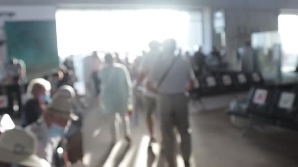 Desfocado por vídeo de pessoas usando máscaras no aeroporto durante a pandemia de Covid-19. A fila para embarque na partida e assentos com sinais especiais de distanciamento social — Vídeo de Stock